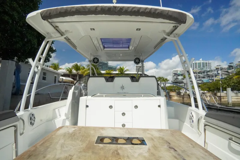  Yacht Photos Pics 2021 Jeanneau Leader 10.5 WA boat interior with table, canopy, and urban backdrop.