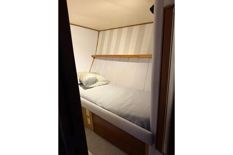  Yacht Photos Pics Cozy cabin bed in 1989 Buddy Davis 61 yacht, featuring striped walls and soft bedding.