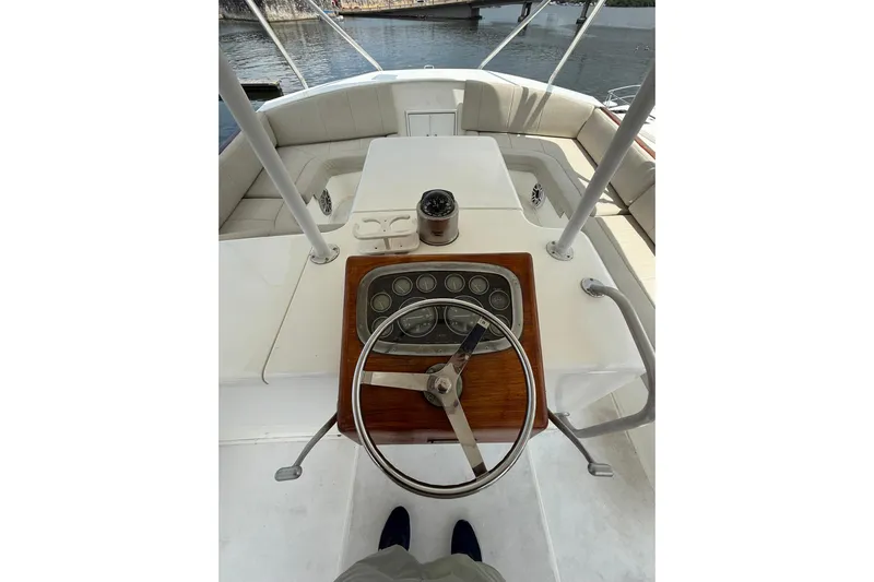  Yacht Photos Pics 1989 Buddy Davis 61 boat helm with steering wheel and gauges, docked on calm water.