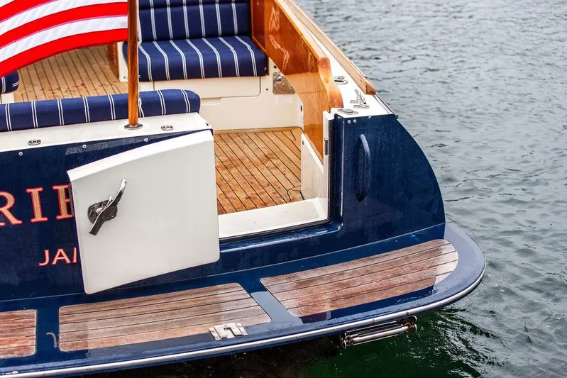 Friendship Yacht Photos Pics Hinckley Picnic Boat MKIII 2010, featuring striped seating and American flag, docked on water.