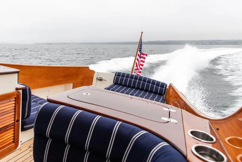 Friendship Yacht Photos Pics Hinckley Picnic Boat MKIII 2010 cruising on water, featuring striped seating and American flag.