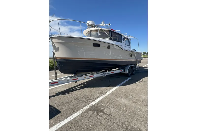 Anima Gemella Yacht Photos Pics 2023 Ranger Tugs R-27 boat on trailer, parked on asphalt under clear blue sky.