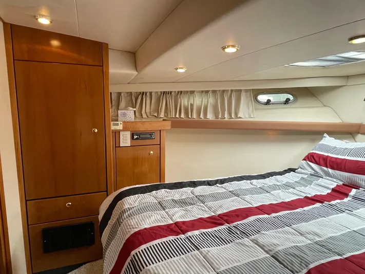 Yacht Photos Pics 1998 Bayliner 4788 Pilot House Motoryacht bedroom with striped bedding and wooden cabinetry.
