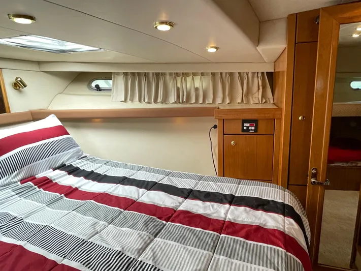 Yacht Photos Pics 1998 Bayliner 4788 Pilot House Motoryacht bedroom with striped bedding and wooden cabinetry.