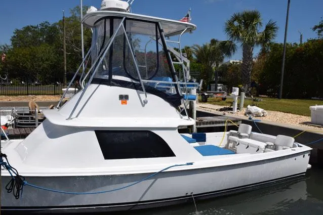 Rampage Yacht Photos Pics 1976 Bertram Flybridge Cruiser docked, featuring sleek design and spacious deck under clear blue sky.