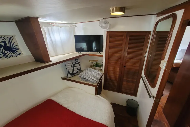  Yacht Photos Pics Cozy cabin interior of 1982 Cheoy Lee 52 yacht with bed, TV, and nautical decor.