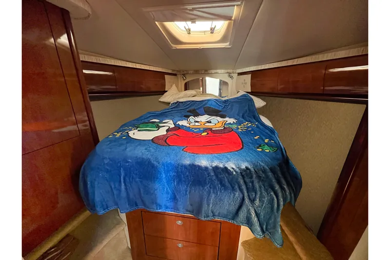 Yacht Photos Pics 2004 Searay 420 Sundancer cabin with cartoon-themed bedspread and wooden cabinetry.