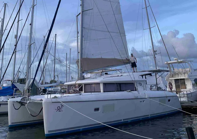 Road Less Travelled Yacht Photos Pics 2013 Lagoon 421 catamaran docked at marina with sails raised, under cloudy sky.