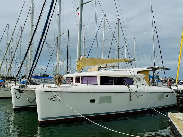 Road Less Travelled Yacht Photos Pics 2013 Lagoon 421 catamaran docked at marina, surrounded by sailboats under cloudy sky.