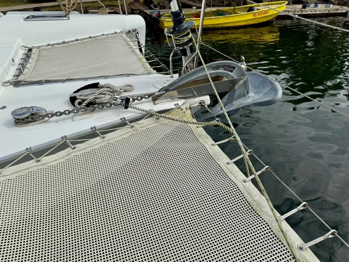 Road Less Travelled Yacht Photos Pics 2013 Lagoon 421 catamaran with anchor and netting, docked near a yellow boat.