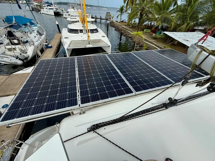Road Less Travelled Yacht Photos Pics 2013 Lagoon 421 catamaran with solar panels docked near palm trees.