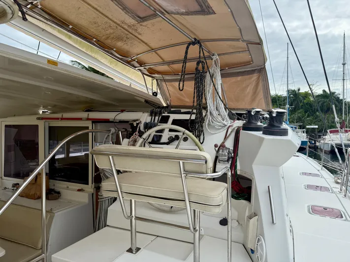 Road Less Travelled Yacht Photos Pics 2013 Lagoon 421 yacht cockpit with helm, ropes, and seating in a marina setting.