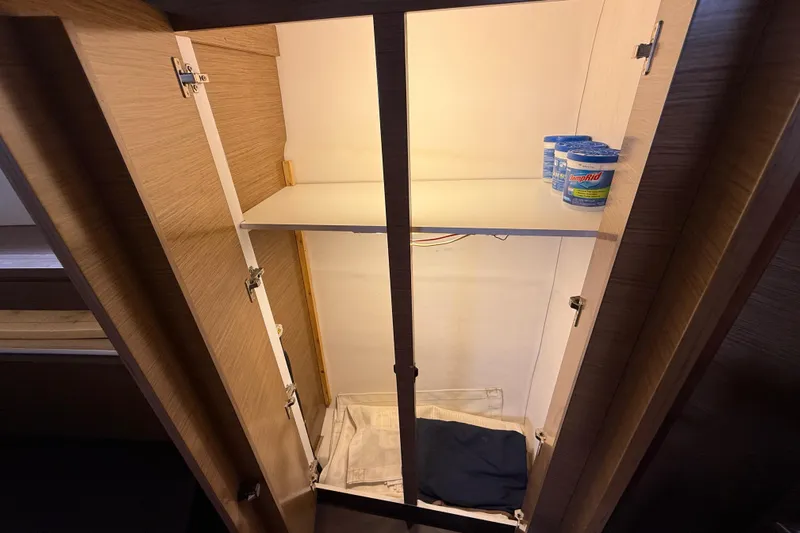 Ohana Yacht Photos Pics Open wooden cabinet with shelves, DampRid containers, and folded fabric inside. Fountaine Pajot Summerland 40 LC, 2015.