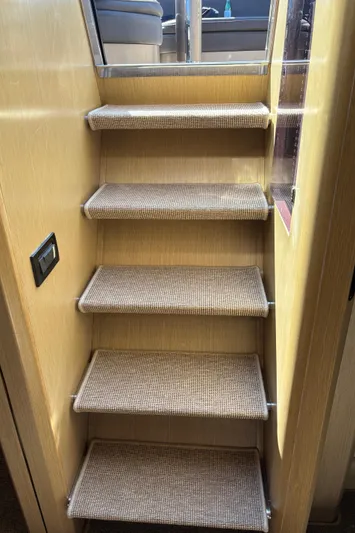 (2021 And 2024 Retrofit) Yacht Photos Pics Staircase inside 2003 Riva 52' LE yacht with carpeted steps and wooden walls.