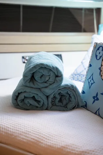 (2021 And 2024 Retrofit) Yacht Photos Pics Rolled blue towels on a bed inside a 2003 Riva 52' le yacht cabin.