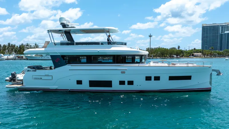 Sand Bar Yacht Photos Pics 2018 Sirena 64 yacht on clear blue water with cityscape background.