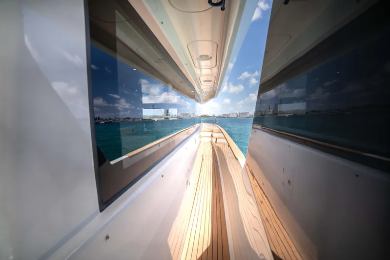 Sand Bar Yacht Photos Pics Side deck view of 2018 Sirena 64 yacht with ocean and cityscape in the background.