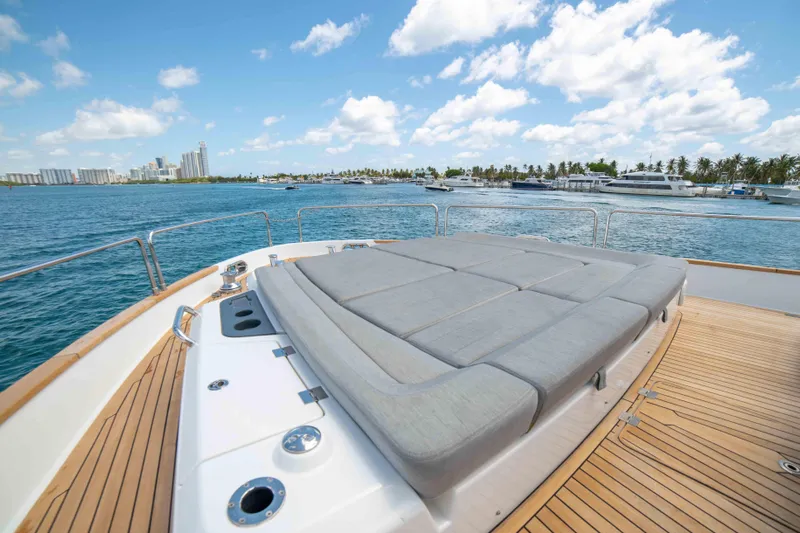 Sand Bar Yacht Photos Pics 2018 Sirena 64 yacht deck with sunbed, ocean view, and city skyline in the background.