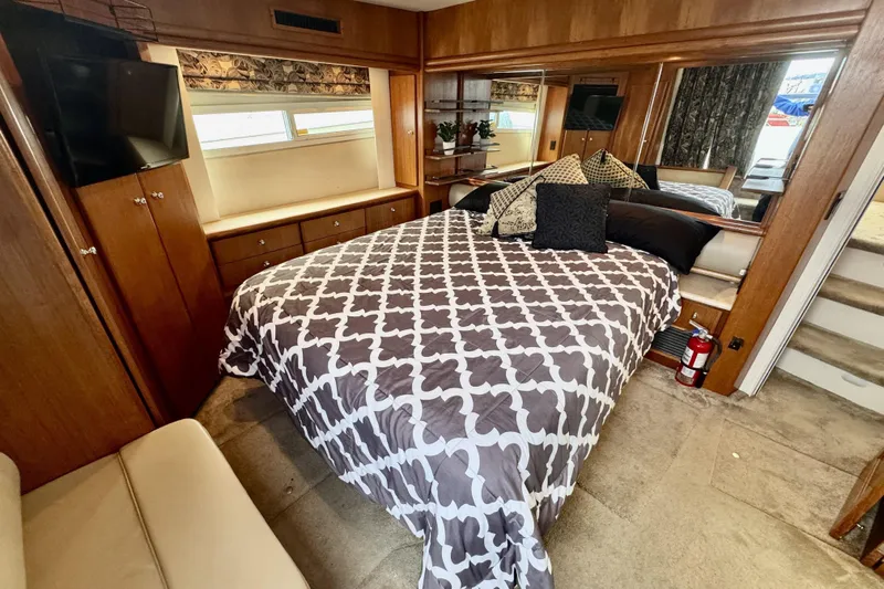 Family Affair IV Yacht Photos Pics Cozy bedroom in 1997 Carver 500 Cockpit Motor Yacht with patterned bedding and wood accents.
