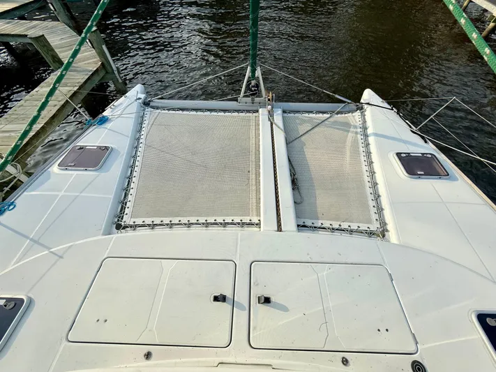 Wander Cat Yacht Photos Pics 2004 Lagoon 380 catamaran deck with netting, docked by the water.