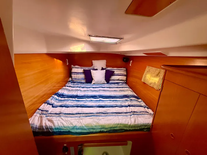 Wander Cat Yacht Photos Pics Cozy cabin interior of 2004 Lagoon 380 catamaran with striped bedding and wooden finish.