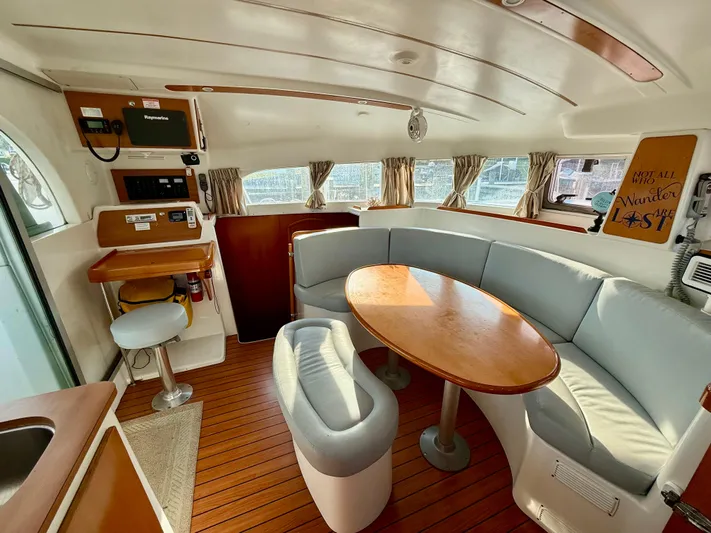 Wander Cat Yacht Photos Pics Interior of 2004 Lagoon 380 catamaran with cozy seating and wooden table.
