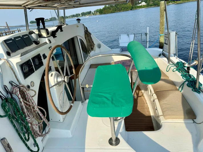 Wander Cat Yacht Photos Pics 2004 Lagoon 380 catamaran cockpit with green seating, steering wheel, and ropes by the water.