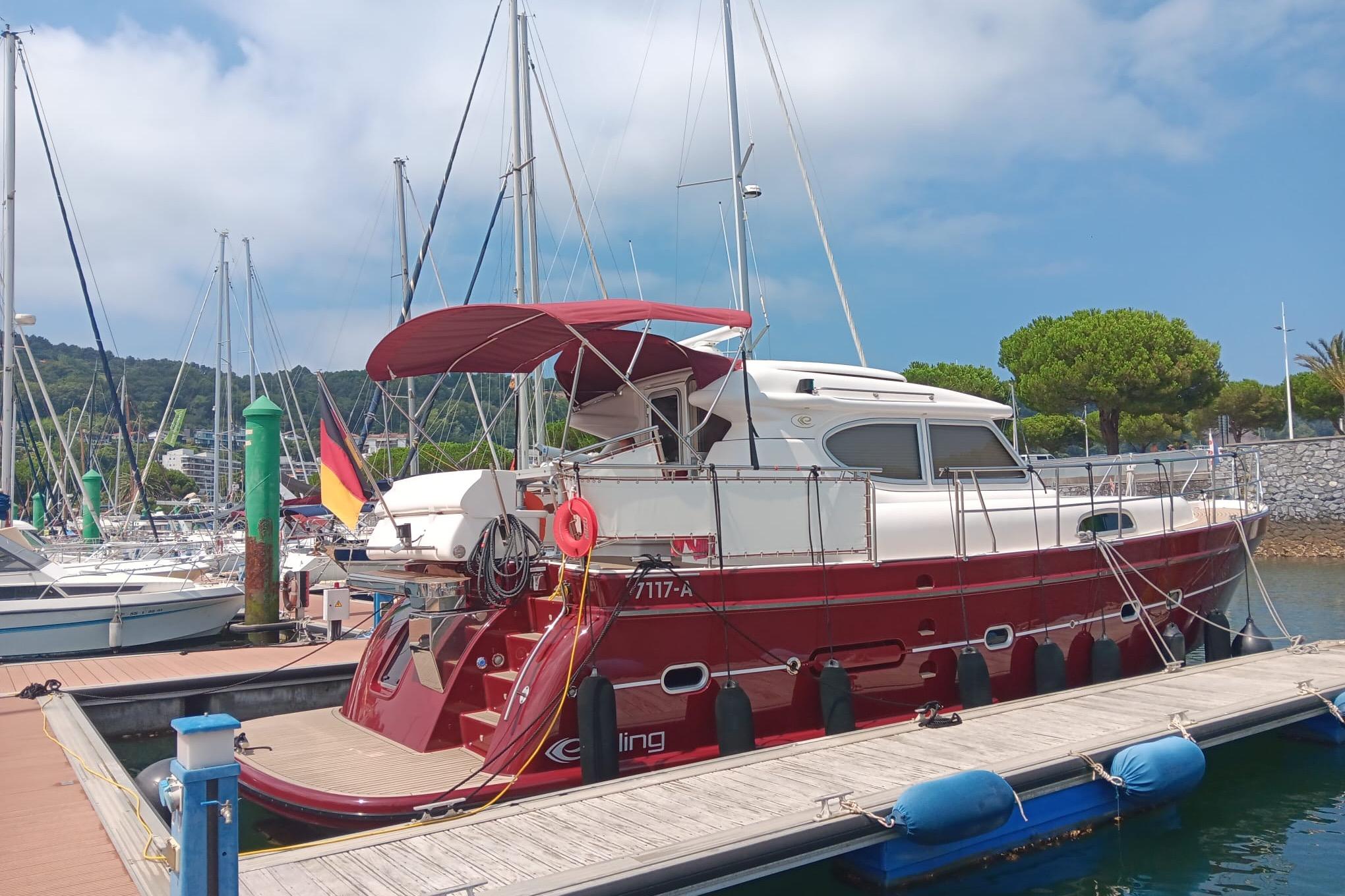 Red 2014 Elling E3 yacht docked at marina under blue sky.