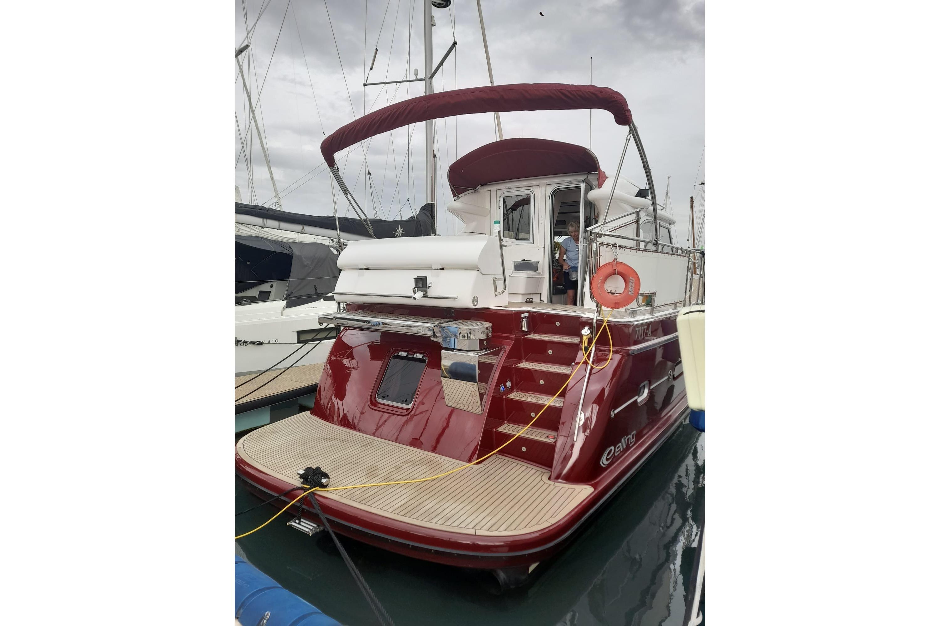 Red 2014 Elling E3 Ultimate yacht docked at marina, featuring a covered deck and lifebuoy.
