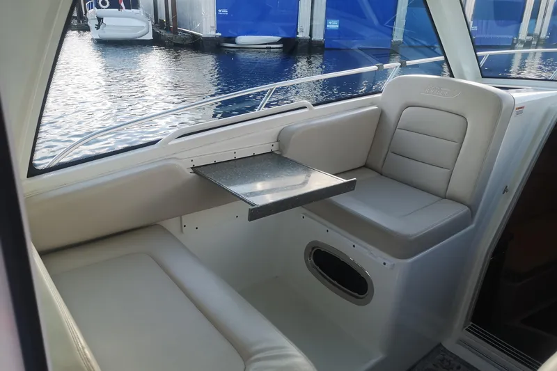  Yacht Photos Pics 2016 Boston Whaler 315 Conquest Pilothouse interior seating with table, docked by water.