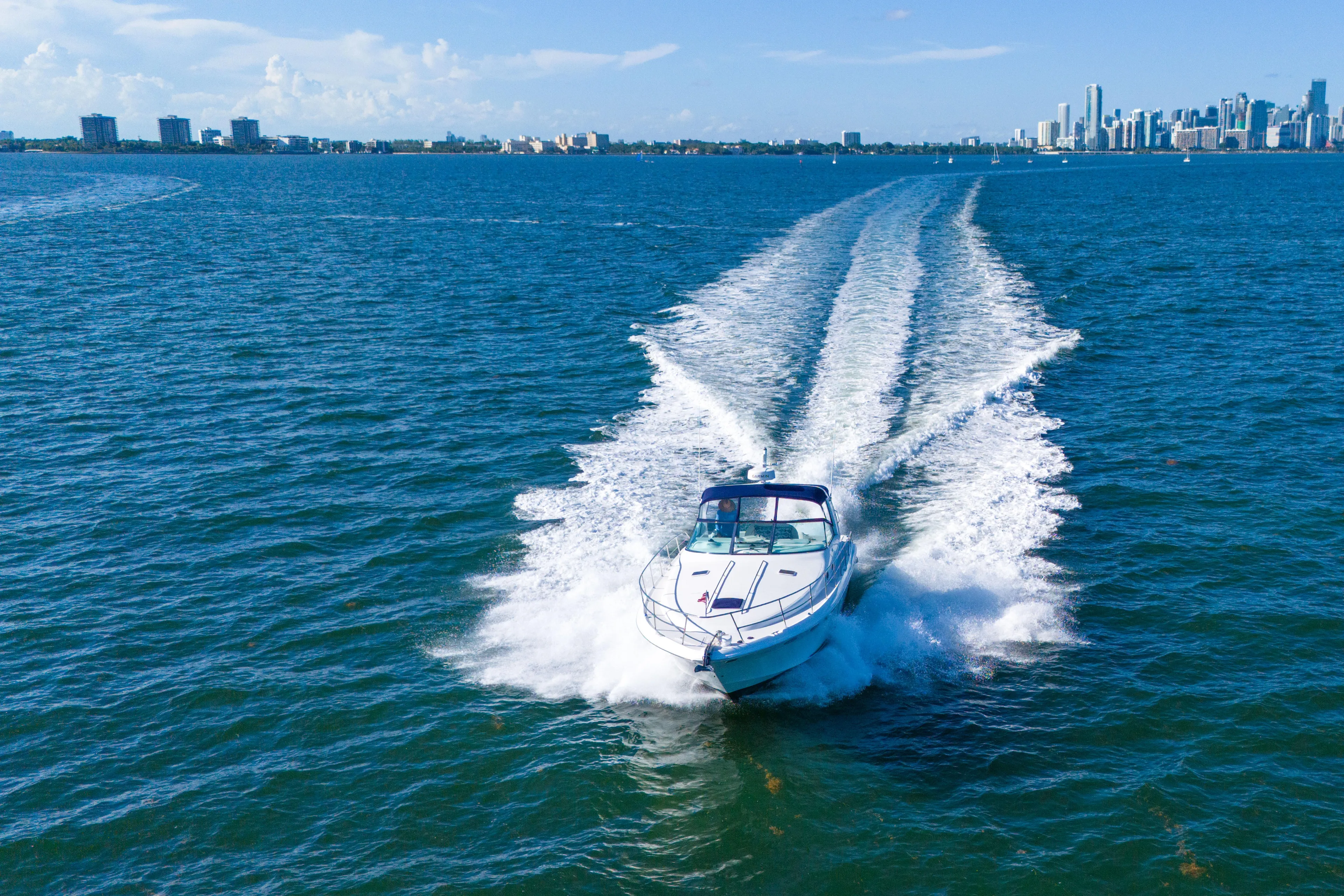  Yacht Photos Pics 1997 Sea Ray 400 Sundancer cruising on blue ocean with city skyline in background.