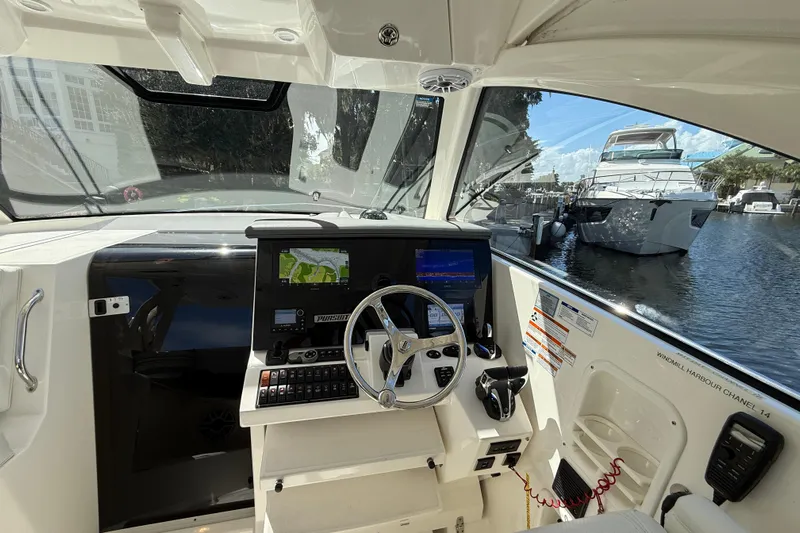Centra Yacht Photos Pics 2023 Pursuit OS 355 Offshore helm with navigation screens, docked near luxury yachts.