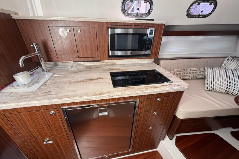 Centra Yacht Photos Pics 2023 Pursuit OS 355 Offshore yacht kitchen with modern appliances and elegant wood finish.