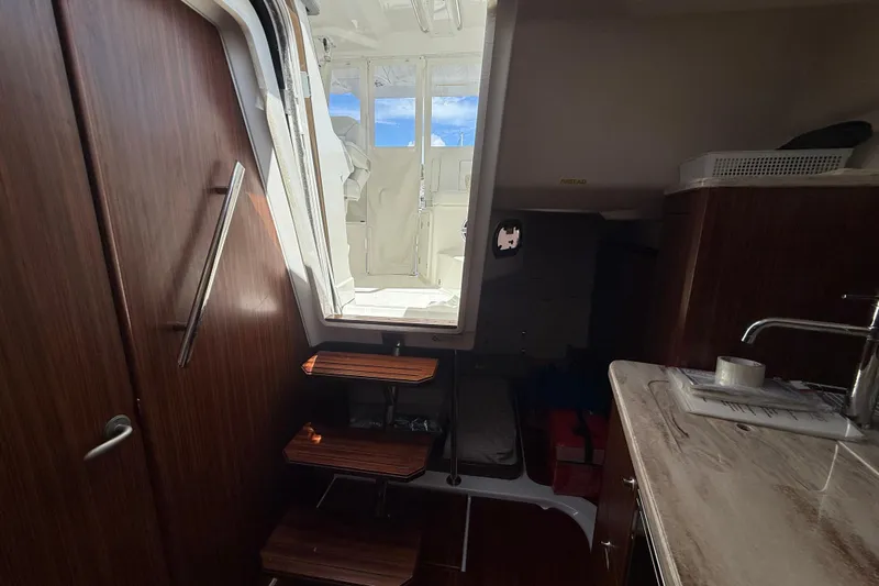 Centra Yacht Photos Pics Interior view of 2023 Pursuit OS 355 Offshore boat, featuring wooden steps and a kitchenette.