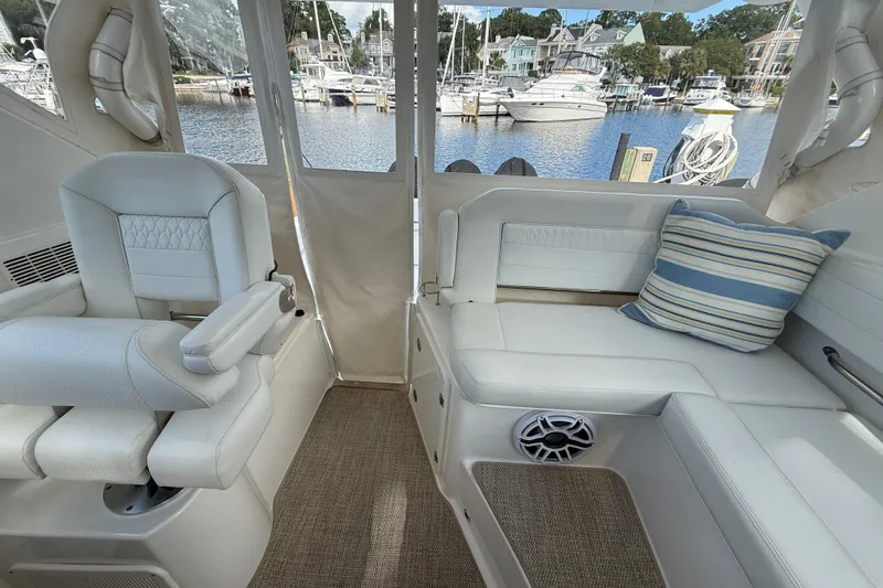 Centra Yacht Photos Pics 2023 Pursuit OS 355 Offshore interior with white seating, striped pillow, and marina view.