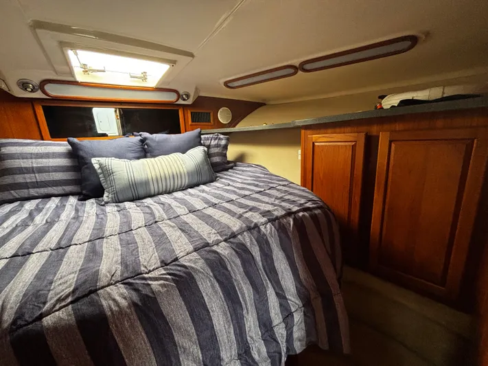 Martuni Yacht Photos Pics 2002 Luhrs 40 Open cabin with striped bedding and wooden cabinetry.