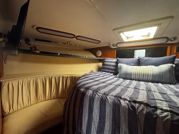 Martuni Yacht Photos Pics Cozy cabin interior of 2002 Luhrs 40 Open yacht with striped bedding and overhead storage.