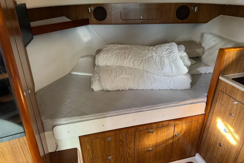  Yacht Photos Pics 2009 Pursuit OS 375 Offshore cabin interior with bed and wooden cabinetry.