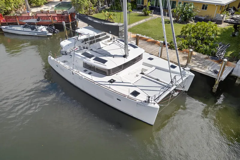  Yacht Photos Pics 2019 Lagoon 450 F catamaran docked by a waterfront home.