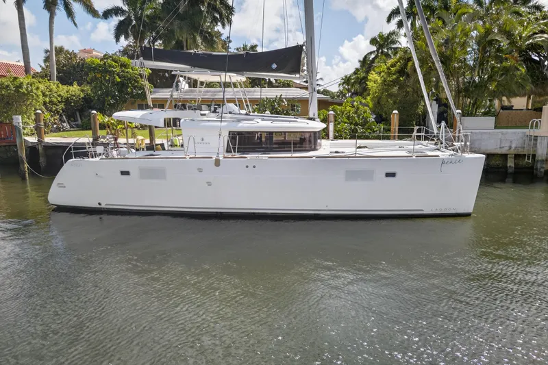  Yacht Photos Pics 2019 Lagoon 450 F catamaran docked by lush greenery and waterfront homes.