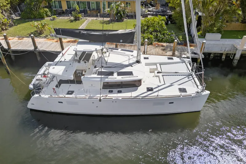  Yacht Photos Pics 2019 Lagoon 450 F catamaran docked by a lush waterfront property.