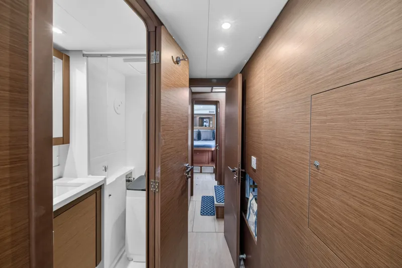  Yacht Photos Pics Interior hallway of 2019 Lagoon 450 F yacht, featuring wood paneling and modern bathroom.