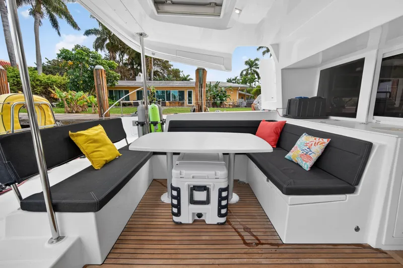  Yacht Photos Pics 2019 Lagoon 450 F yacht cockpit with cushioned seating, table, and colorful pillows.