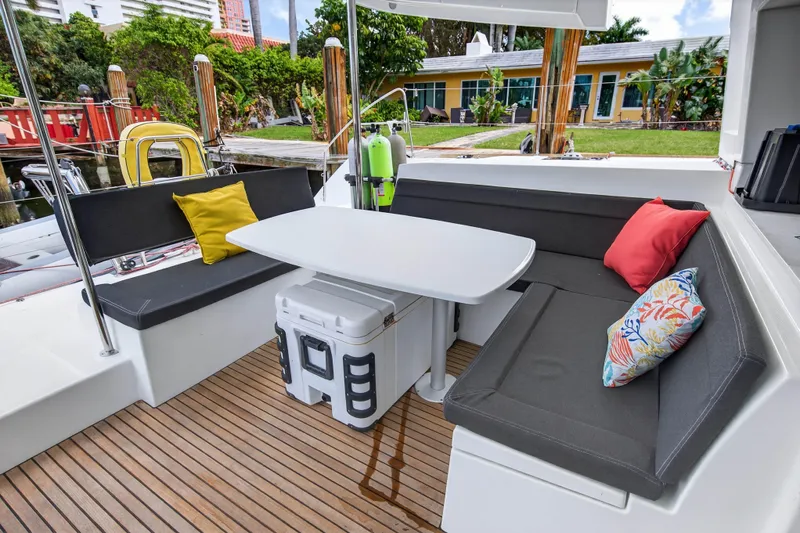  Yacht Photos Pics 2019 Lagoon 450 F yacht deck with cushioned seating and table, featuring colorful pillows.