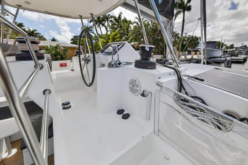  Yacht Photos Pics 2019 Lagoon 450 F yacht cockpit with steering wheel and winch, docked near palm trees.