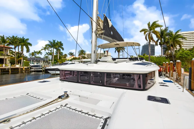  Yacht Photos Pics 2019 Lagoon 450 F catamaran docked, surrounded by palm trees and clear blue sky.