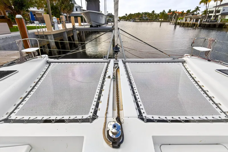  Yacht Photos Pics 2019 Lagoon 450 F catamaran docked, featuring spacious deck and netting, in a serene waterfront setting.