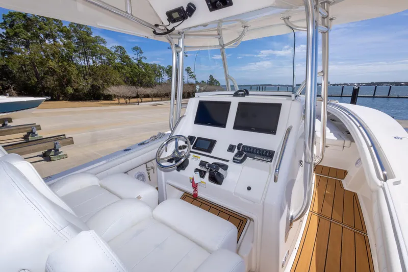 Change Order Yacht Photos Pics 2018 Regulator 31 boat cockpit with dual screens and white seating, docked by the water.