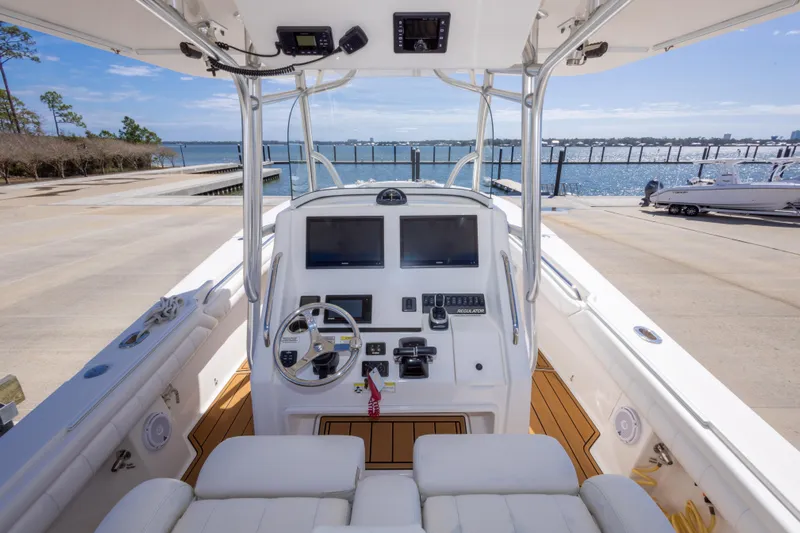 Change Order Yacht Photos Pics 2018 Regulator 31 boat cockpit with dual screens, steering wheel, and waterfront view.