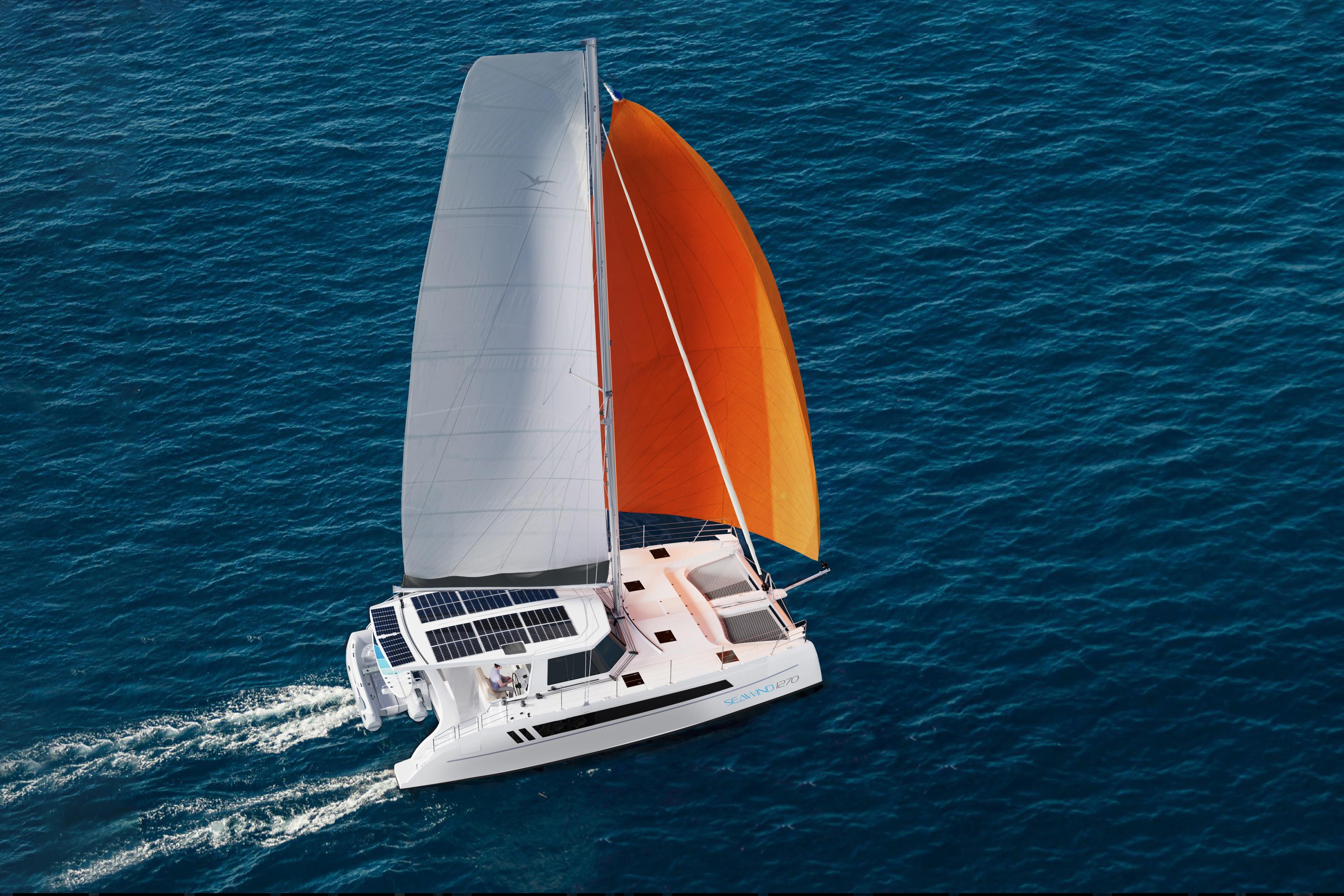2026 Seawind 1270 catamaran sailing with orange and white sails on open ocean.